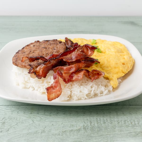 Hawaiian breakfast plate with rice, sausage patty, crispy bacon, and scrambled eggs.