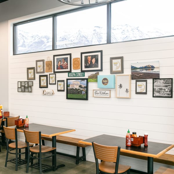 Interior of Budda's Hawaiian Bakery & Grill with tables, chairs, and a wall gallery of Hawaiian-themed pictures.